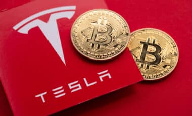 Bitcoin cryptocurrency on a Tesla electric vehicle logo